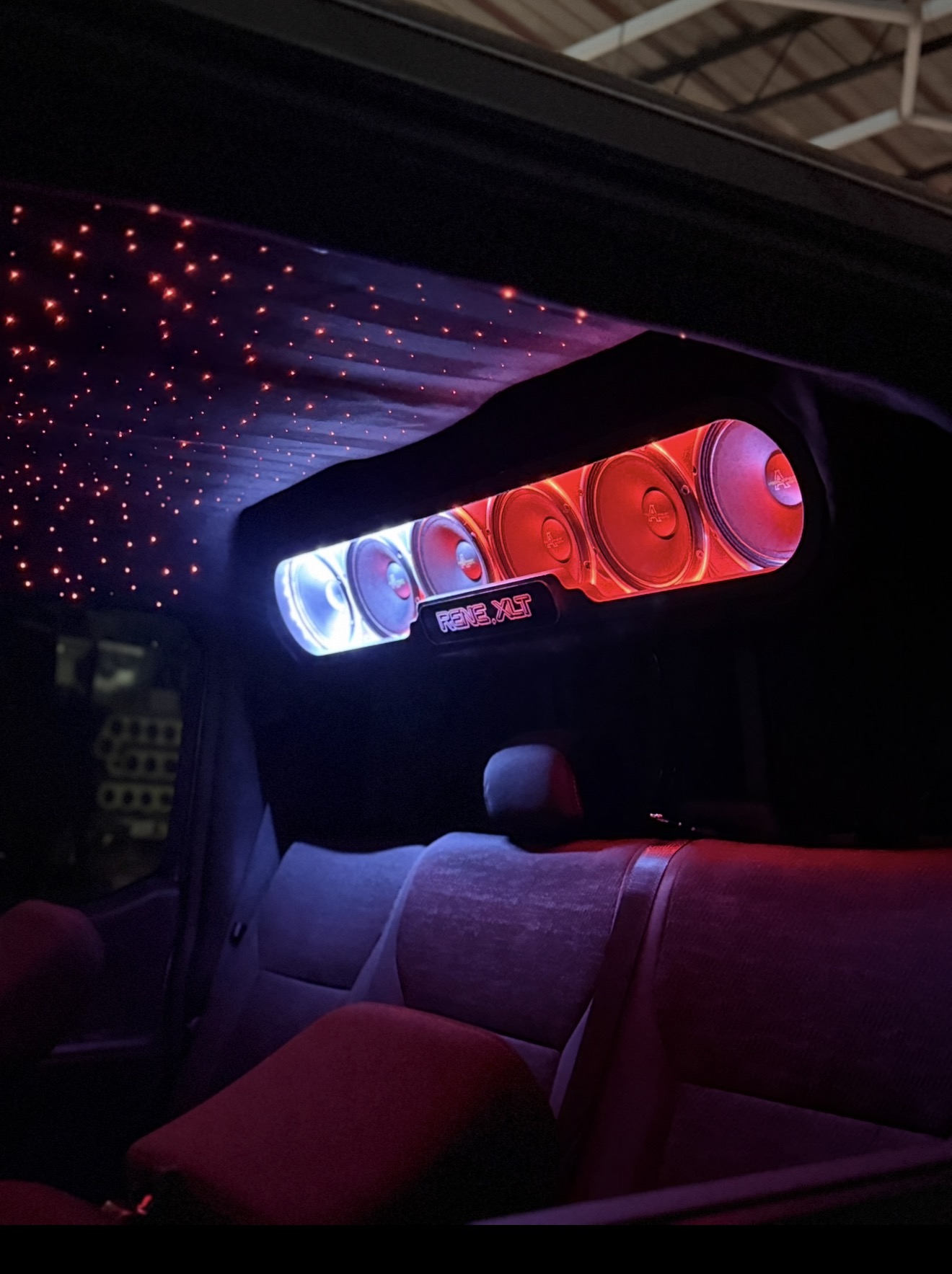 Overhead speaker bar with red lighting, custom name plate and red starlight headliner