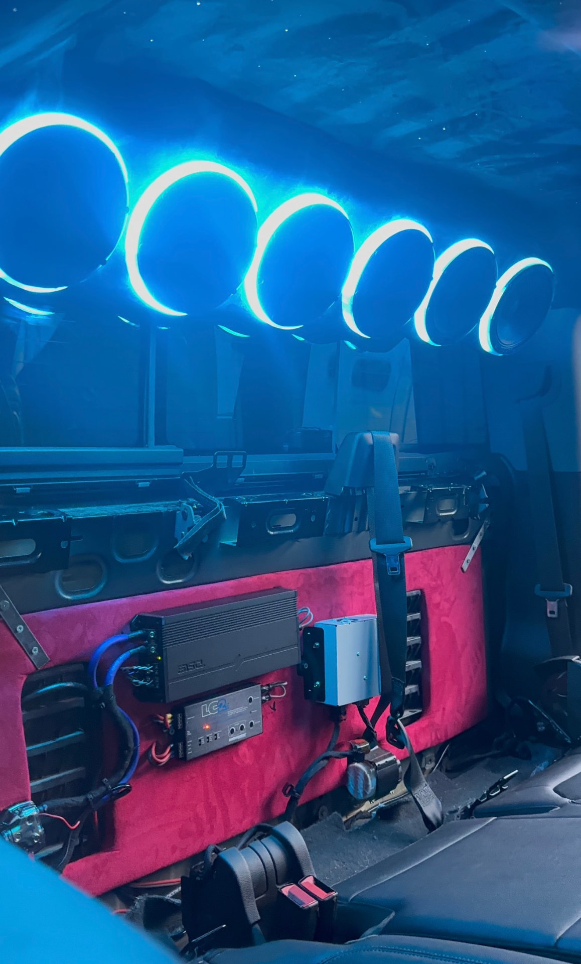 Overhead speaker rack with blue halo rings above a pink suede amp rack install