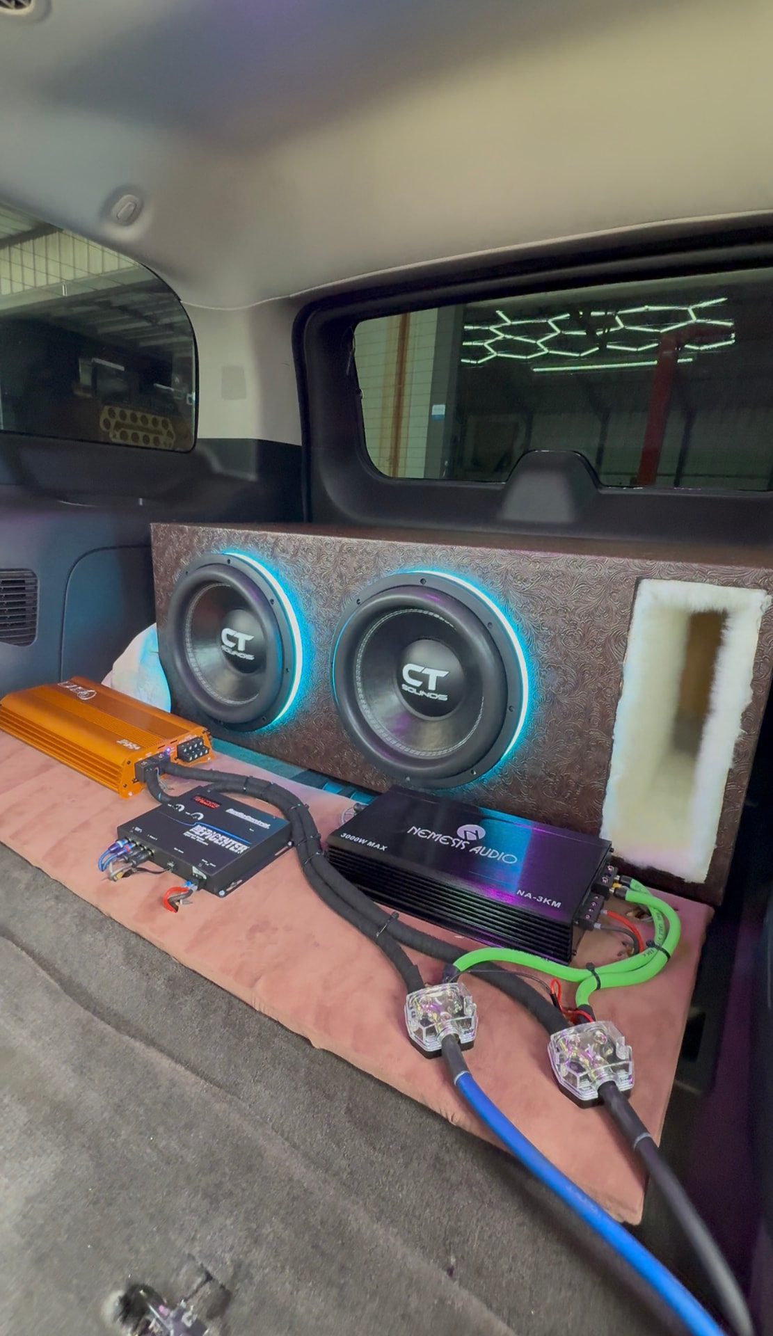 Tooled-leather subwoofer box with halo-lit CT Sounds subs and amp rack in an SUV cargo area